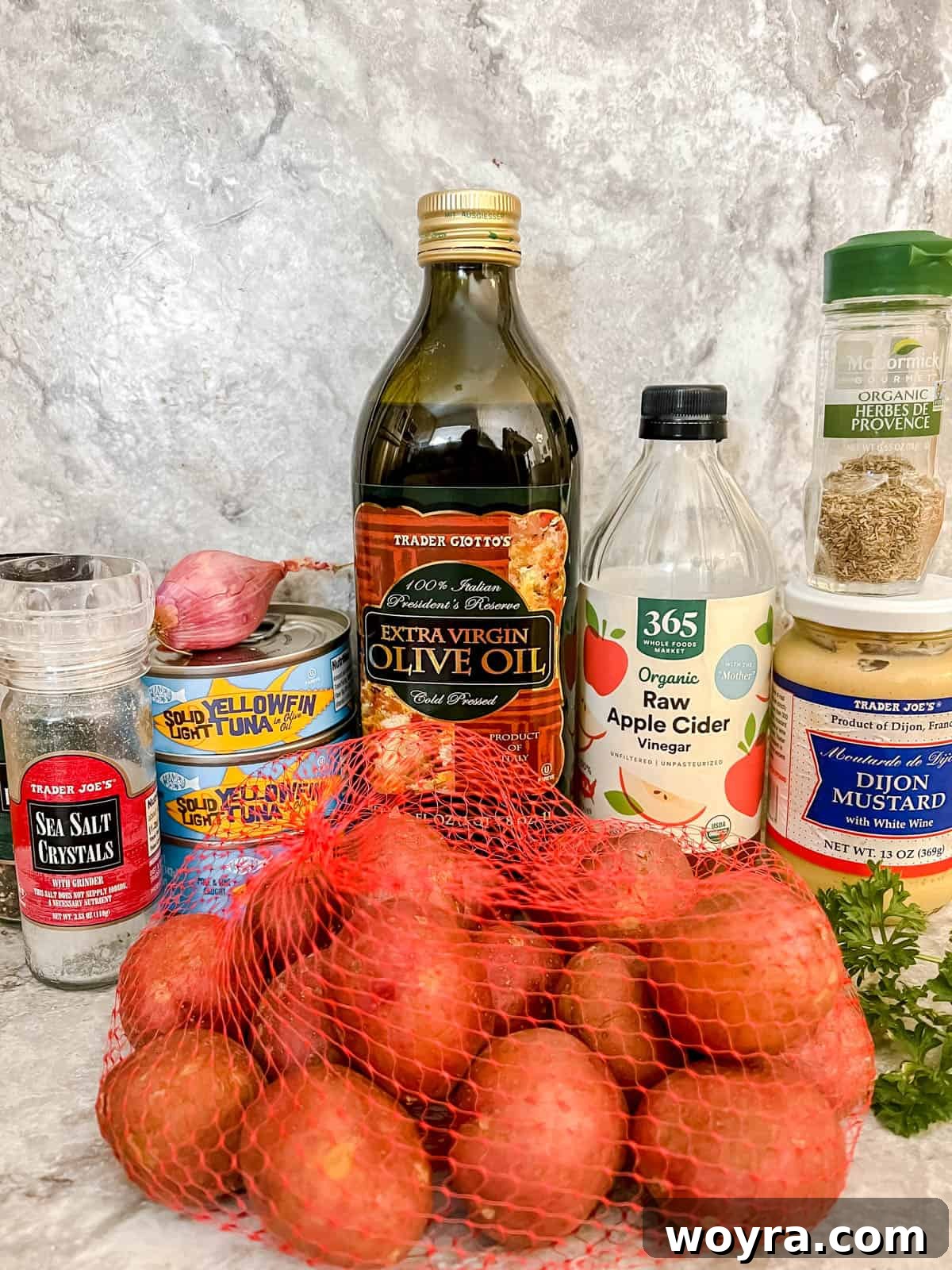 Paleo Whole30 French Tuna Potato Salad 3 A flat lay image showing all the fresh ingredients needed to make a delicious tuna potato salad: potatoes, canned tuna, onions, scallions, olive oil, tarragon vinegar, Dijon mustard, herbes de Provence, and fresh parsley.