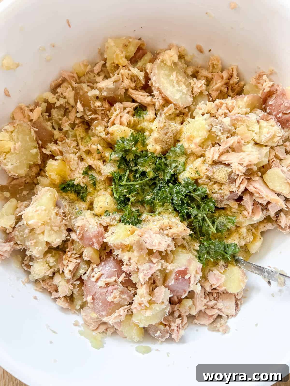 Paleo Whole30 French Tuna Potato Salad 8 Diced onions, sliced scallions, and the French dressing being added to the bowl of tuna and potatoes.