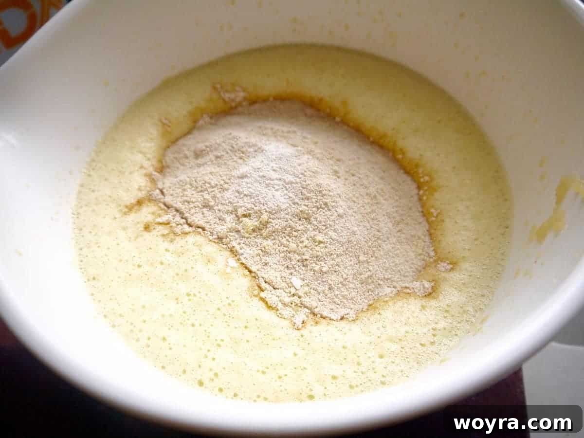 Mixing the wet ingredients in a bowl for the waffle batter, creating a frothy consistency.