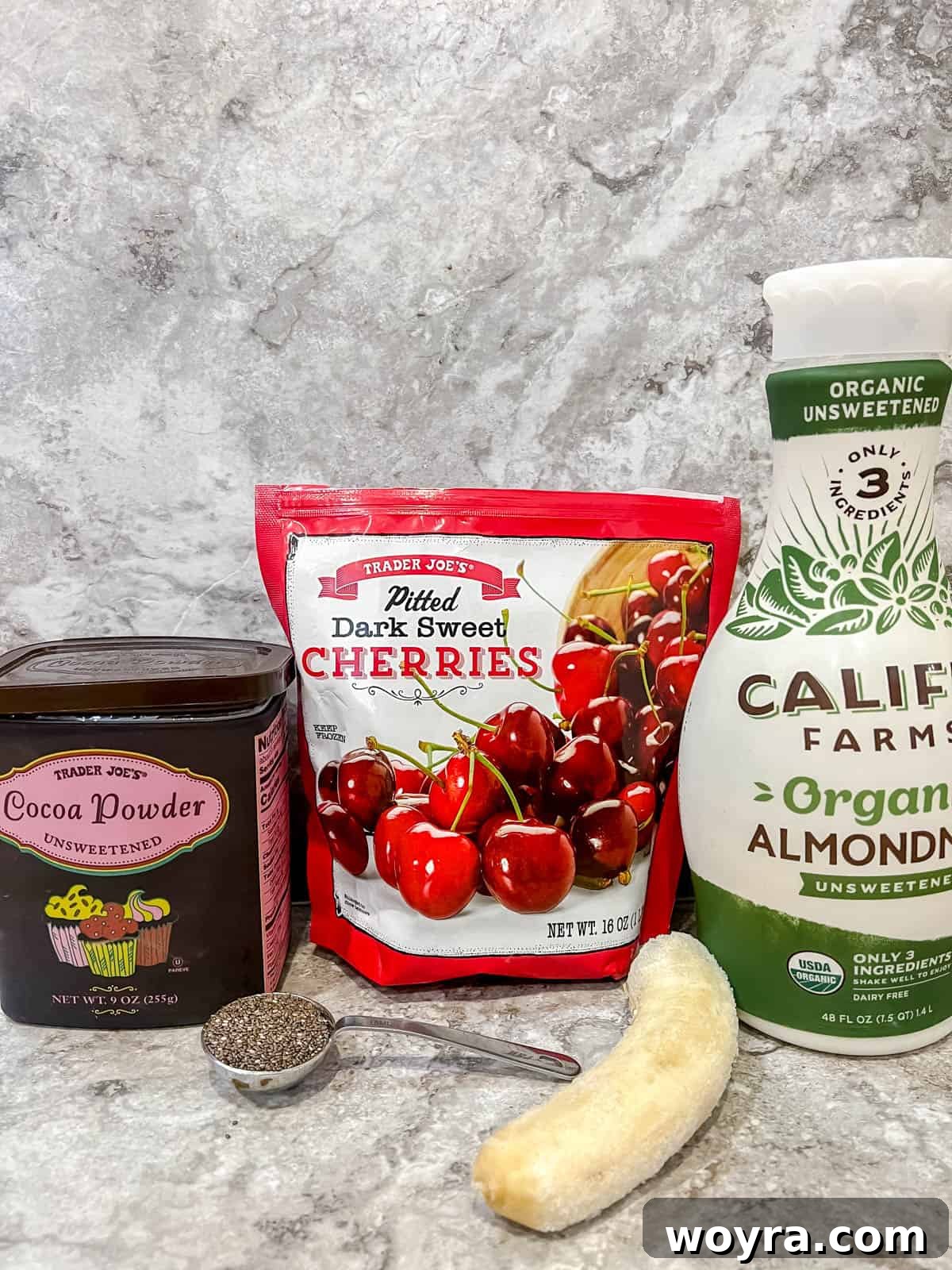 Chocolate Cherry Banana Dream Smoothie 3 Arrangement of ingredients needed to prepare a cherry cocoa smoothie, including frozen fruit and milk.