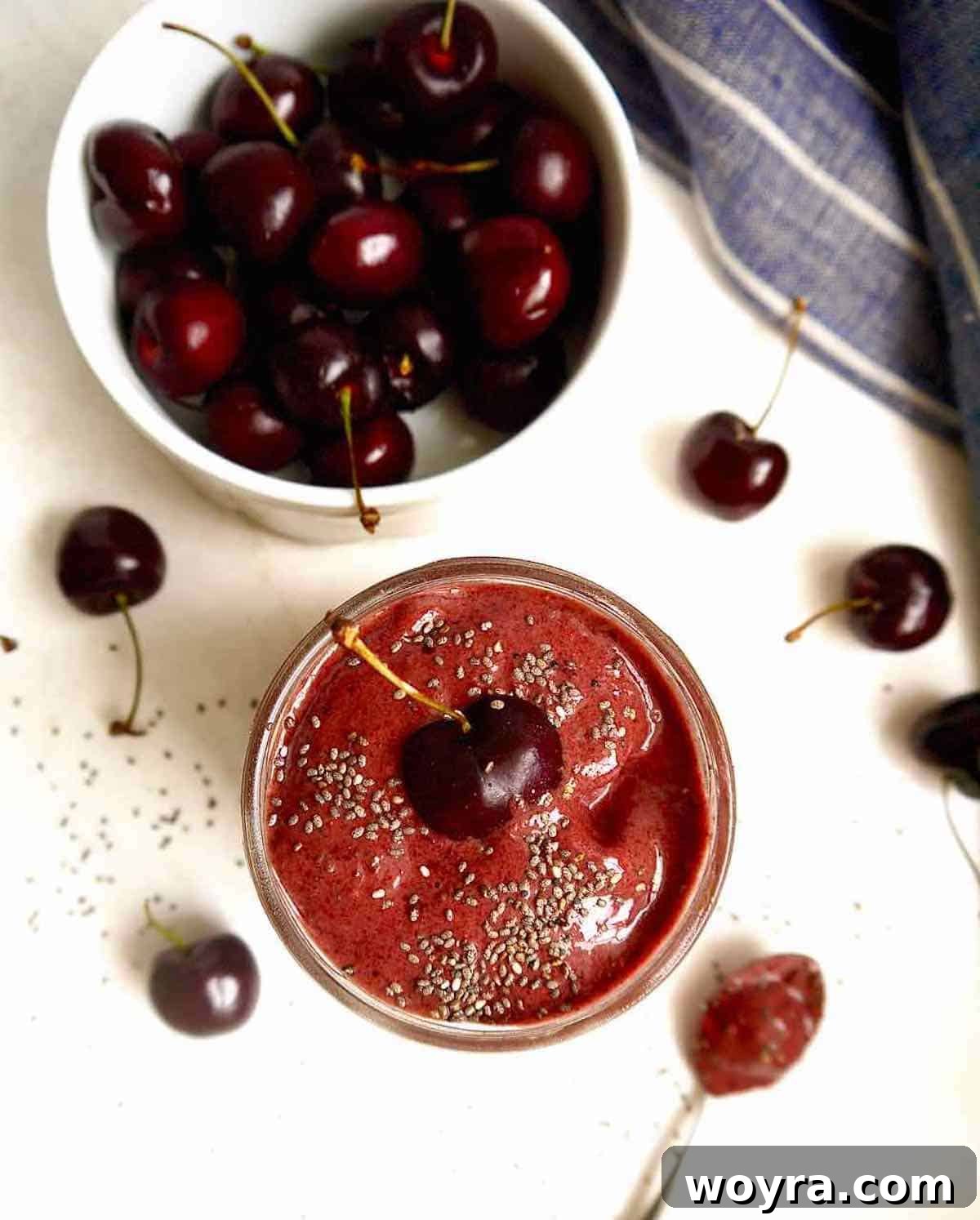 Chocolate Cherry Banana Dream Smoothie 5 A chocolate cherry banana smoothie in a glass jar, with a bowl of fresh cherries beside it.