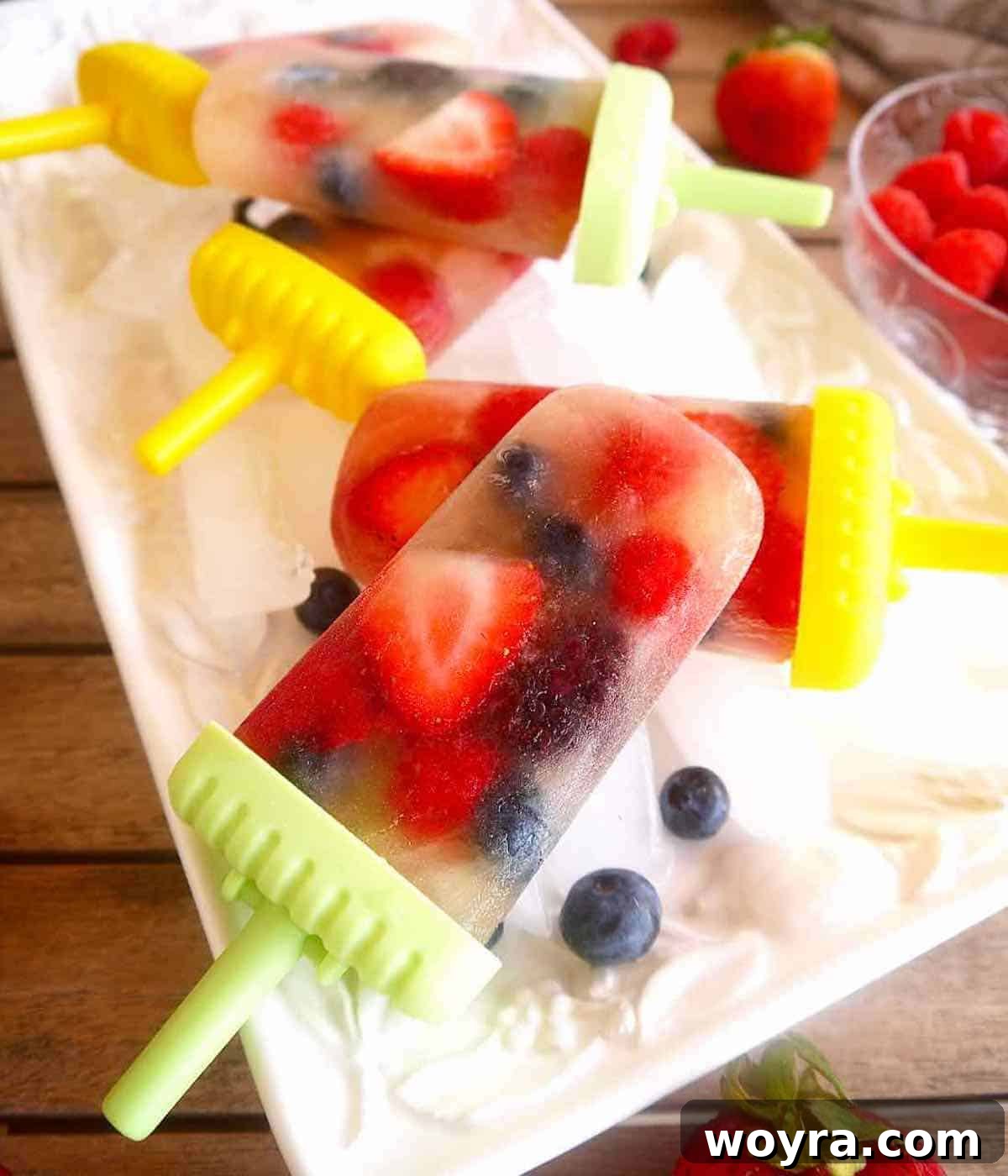 Apple Berry Freeze Pops 3 Collection of Apple juice popsicles with berries displayed on a bed of ice.