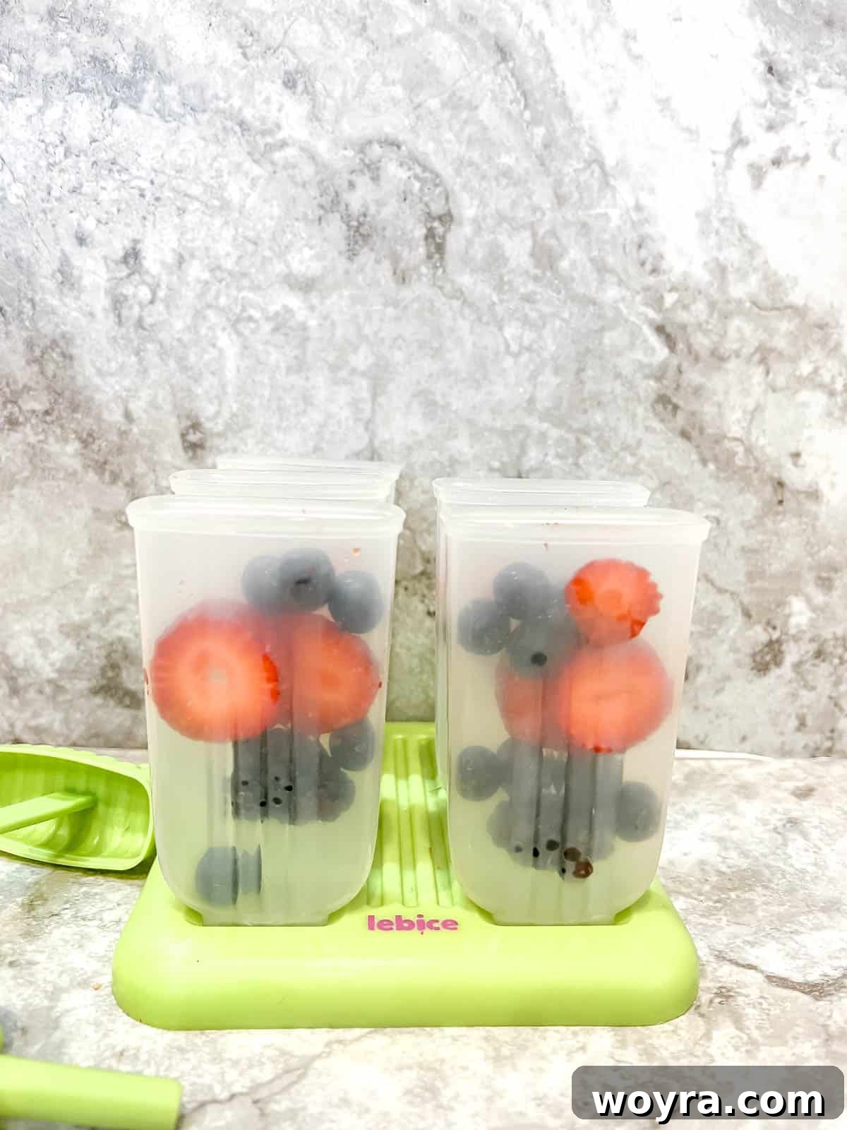 Orchard Berry Pops 5 Popsicle molds meticulously filled with a colorful and enticing assortment of fresh mixed berries, patiently awaiting the addition of liquid.