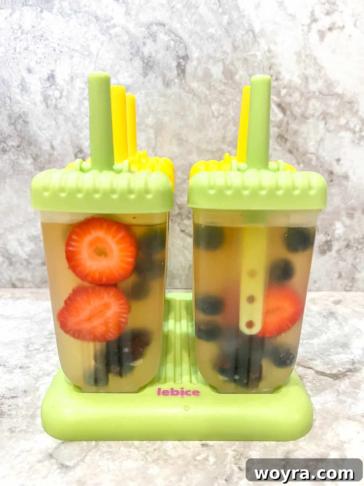 Apple Berry Freeze Pops 7 Popsicle sticks or lids being placed onto the filled popsicle molds.