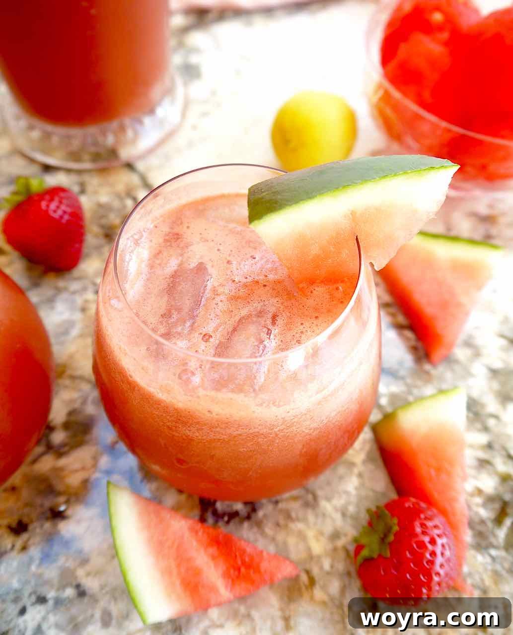 Strawberry Watermelon Cucumber Cooler 5 A glass of watermelon cucumber juice garnished with strawberries and a slice of cucumber on the rim.