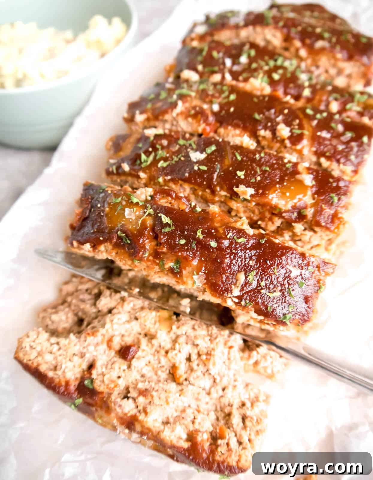 Clean Paleo Meatloaf 12 Paleo meatloaf covered in meatloaf sauce, sliced and ready to serve on a cutting board.