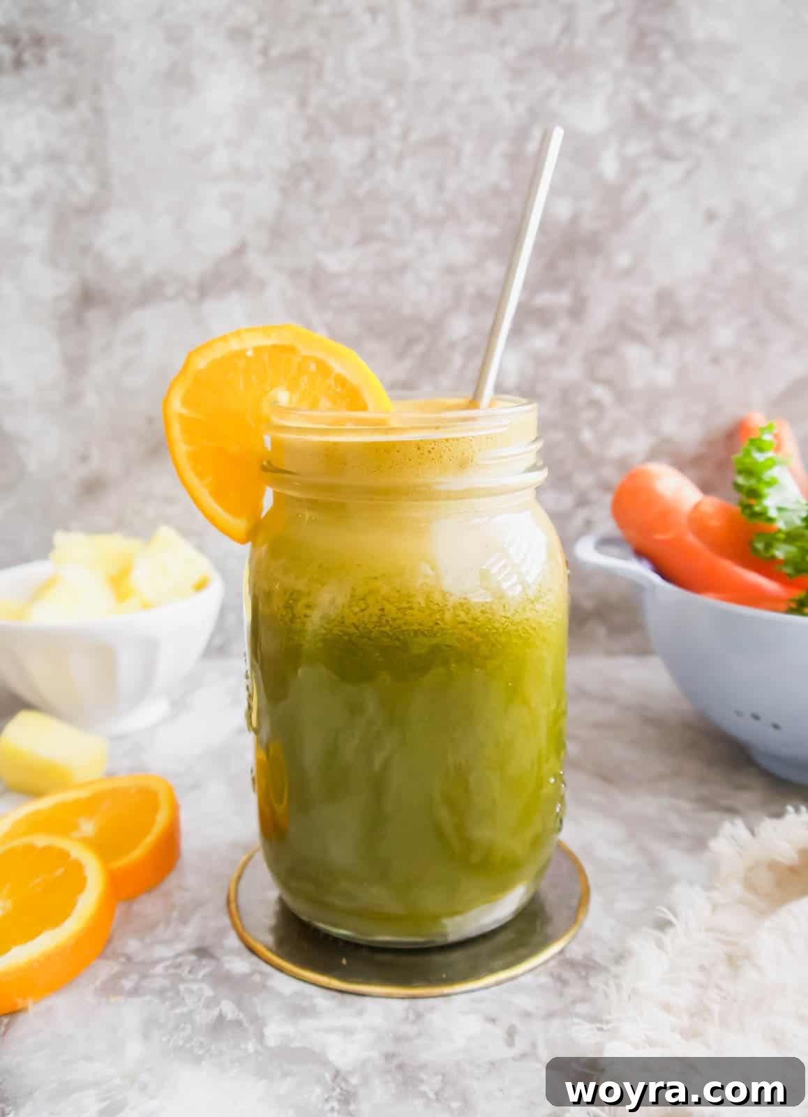 Green & Golden Tropical Quench 4 A vibrant glass of tropical kale and orange juice with a straw, ready for consumption.