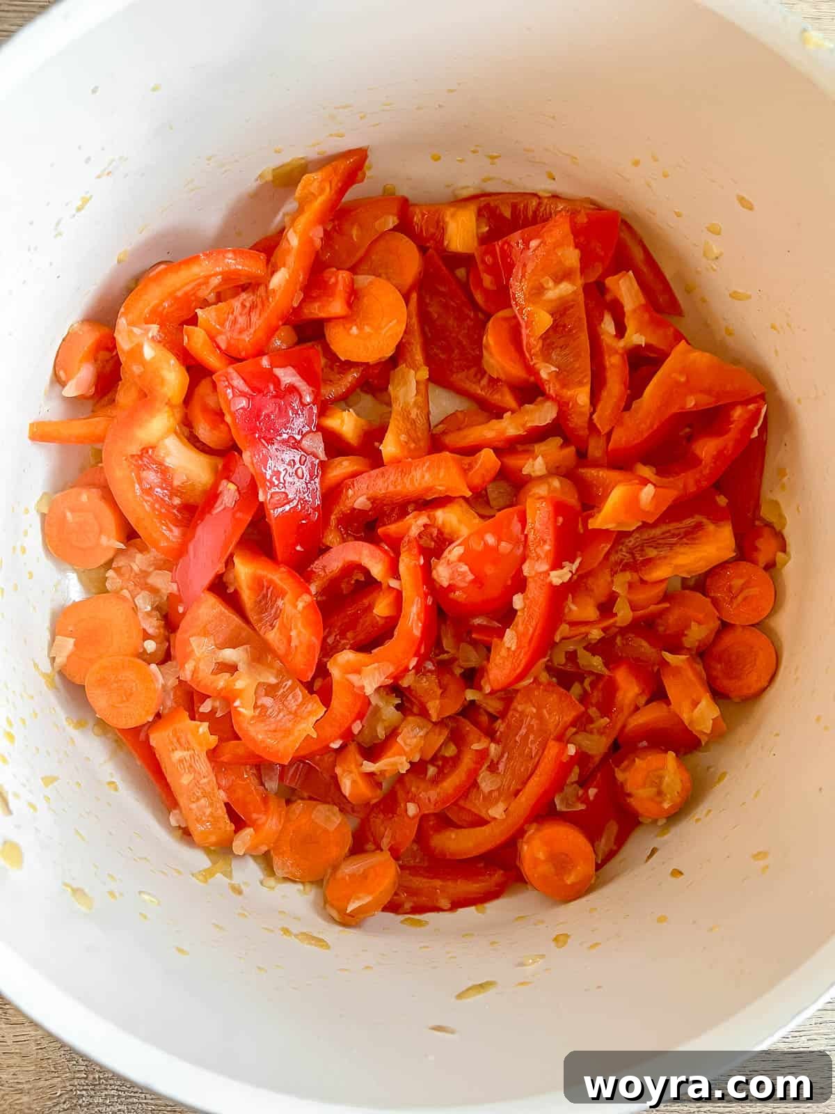 Plant-Based Paleo Thai Red Curry 5 Adding sliced bell peppers and carrots to the sautéed aromatics in a pan.