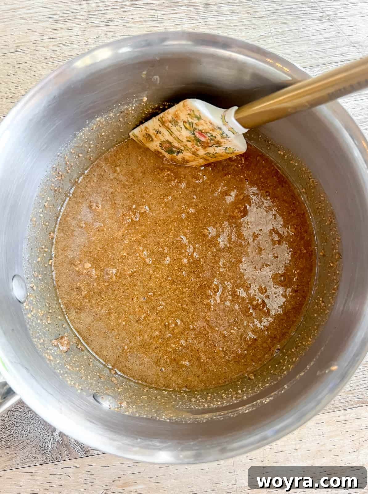 A small saucepan with melted honey, almond butter, and vanilla extract, forming a smooth, warm mixture.