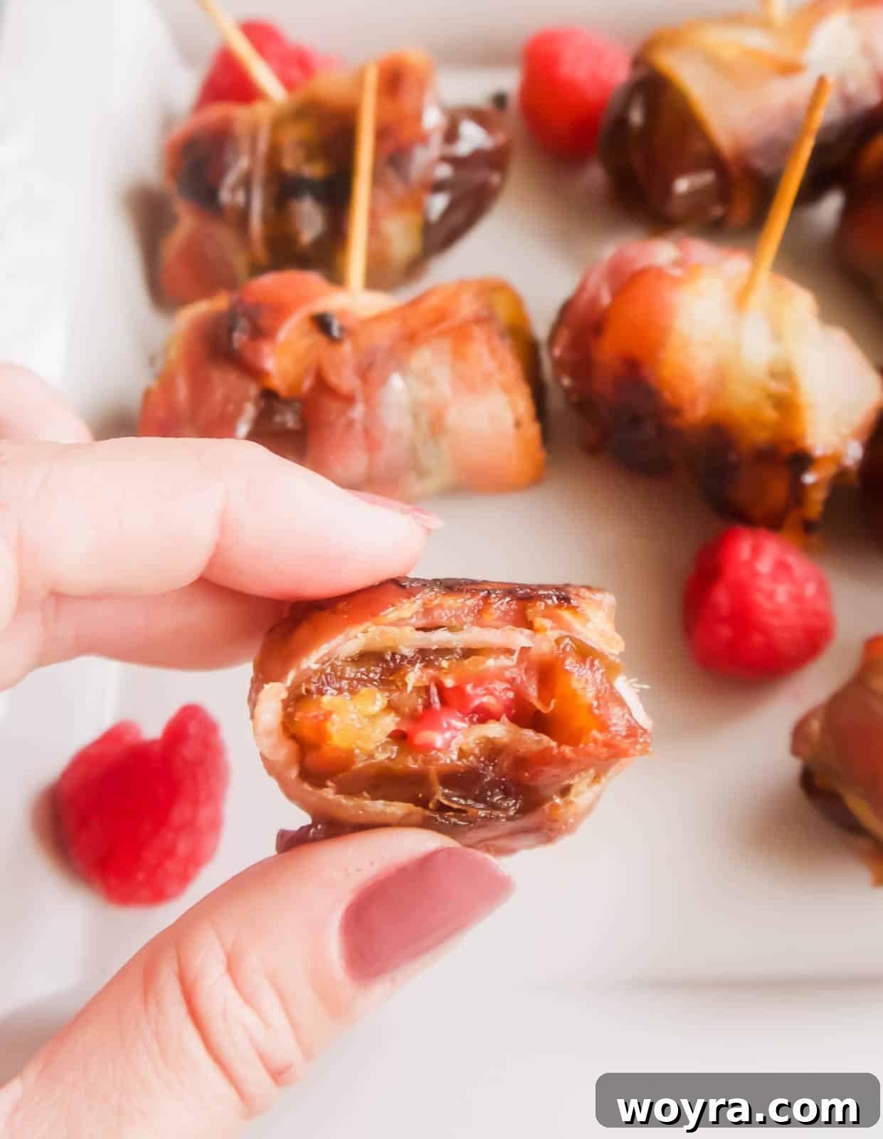 Crispy Bacon-Wrapped Raspberry Stuffed Dates 9 A bite taken out of a date with raspberries inside.