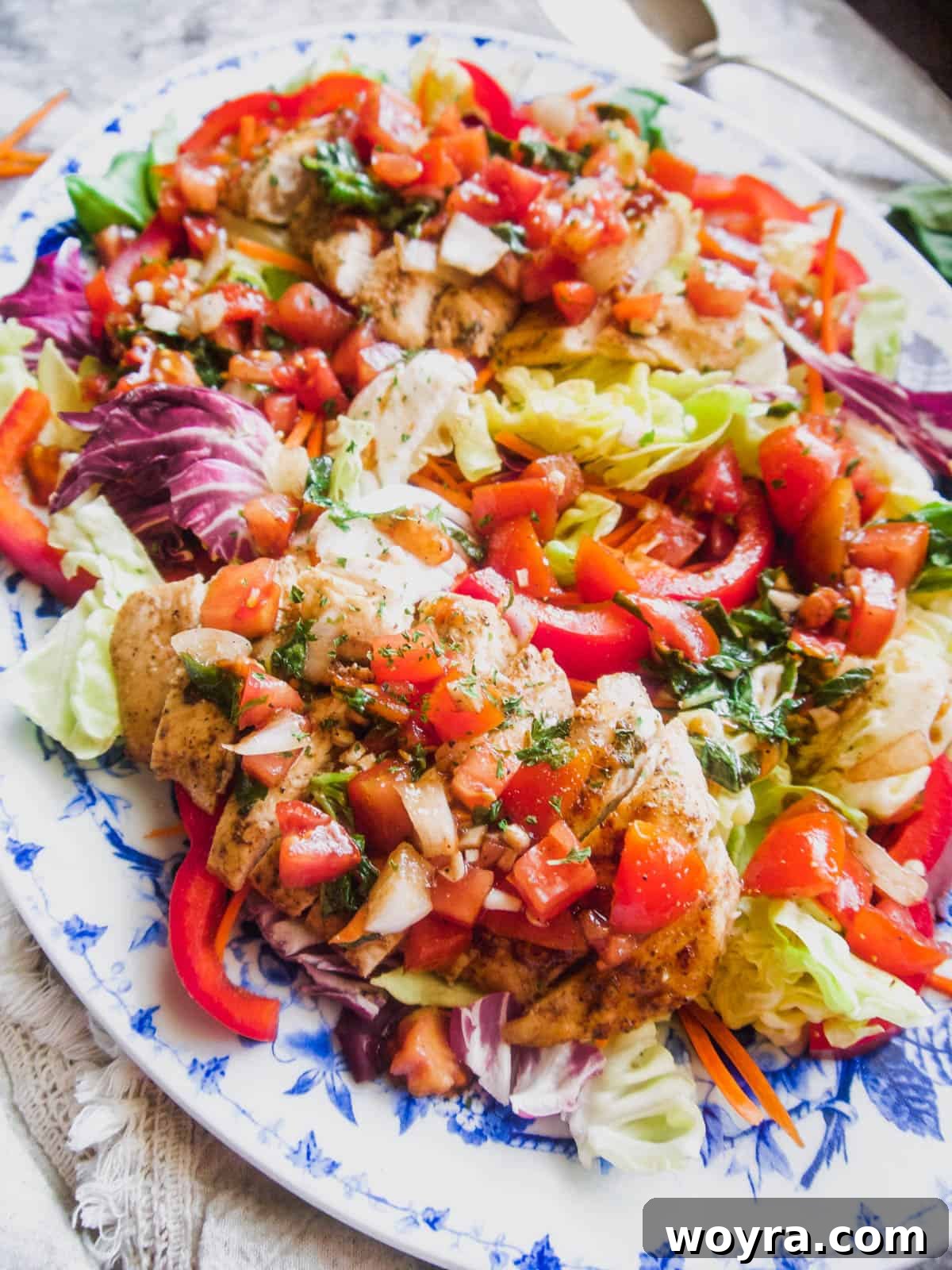A vibrant close-up of the chicken bruschetta salad, highlighting the fresh basil and grilled chicken.