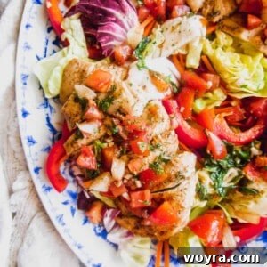 Chicken bruschetta salad on a plate with dressing on top.