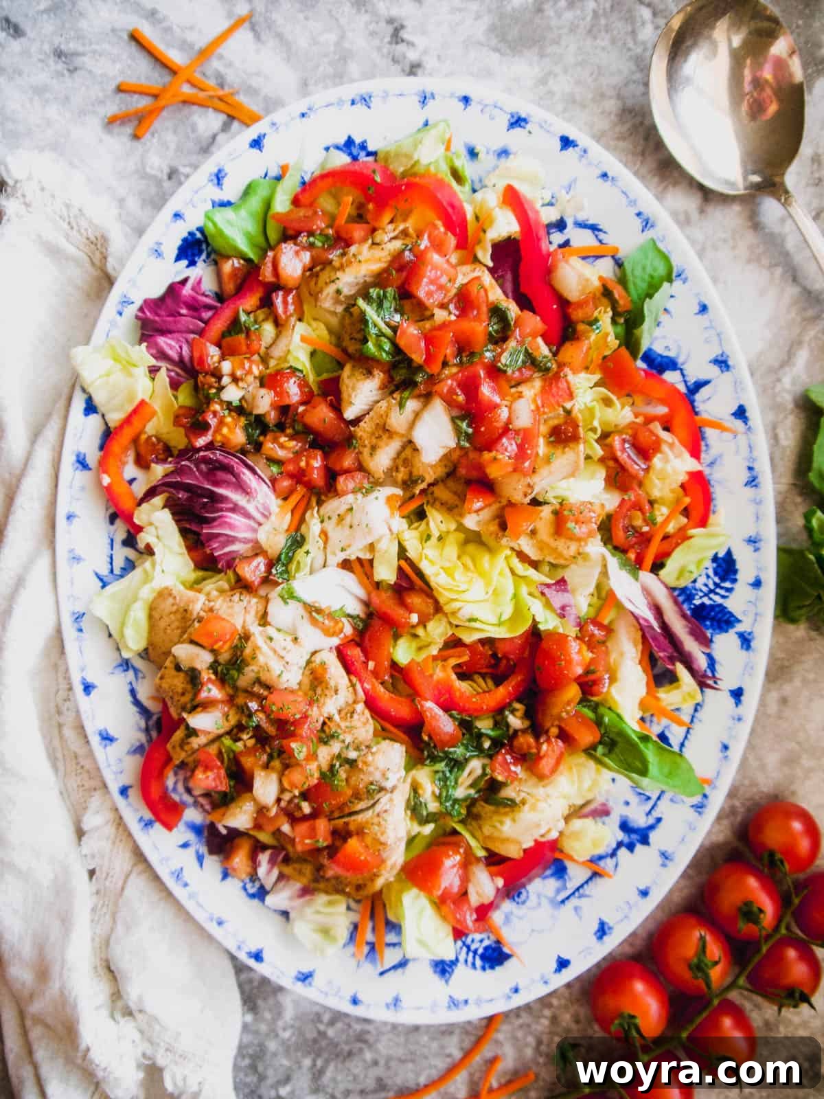 Close-up of a large serving plate filled with chicken bruschetta salad, showcasing the fresh ingredients.