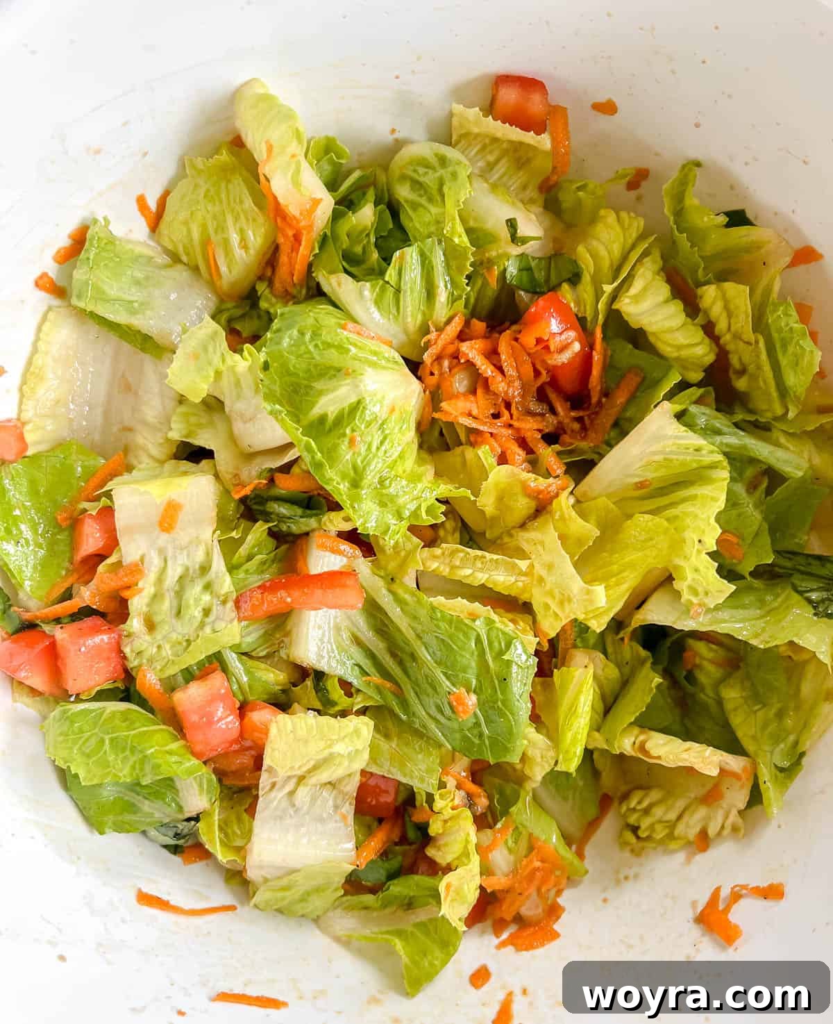 A large bowl containing mixed salad greens, carrots, and red pepper with bruschetta dressing.