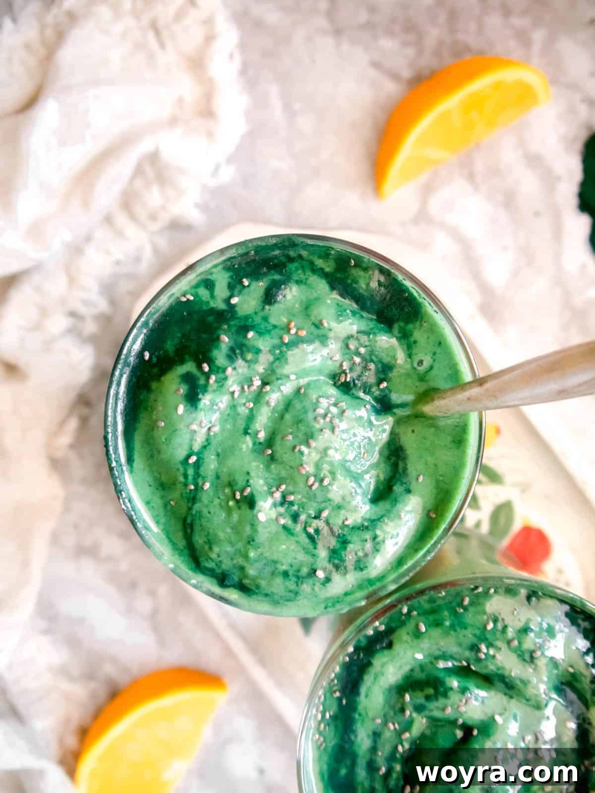 Spirulina Sunshine Smoothie 5 An inviting aerial shot of a creamy green mango spirulina smoothie, served in a glass with a spoon inside, highlighting its rich and thick texture, ready to be enjoyed.