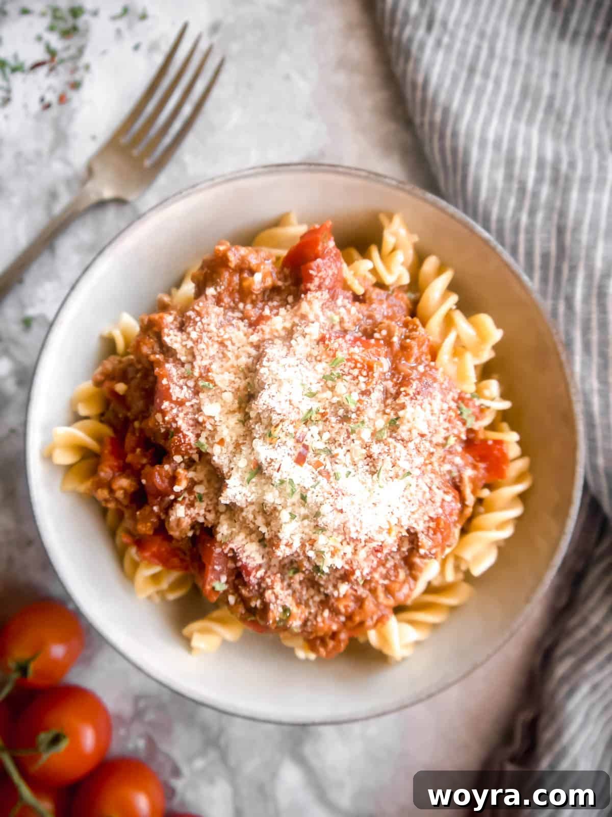 Fiery Homestyle Meat Ragu 5 Spicy meat sauce served on a bed of pasta, garnished with fresh Parmesan cheese.