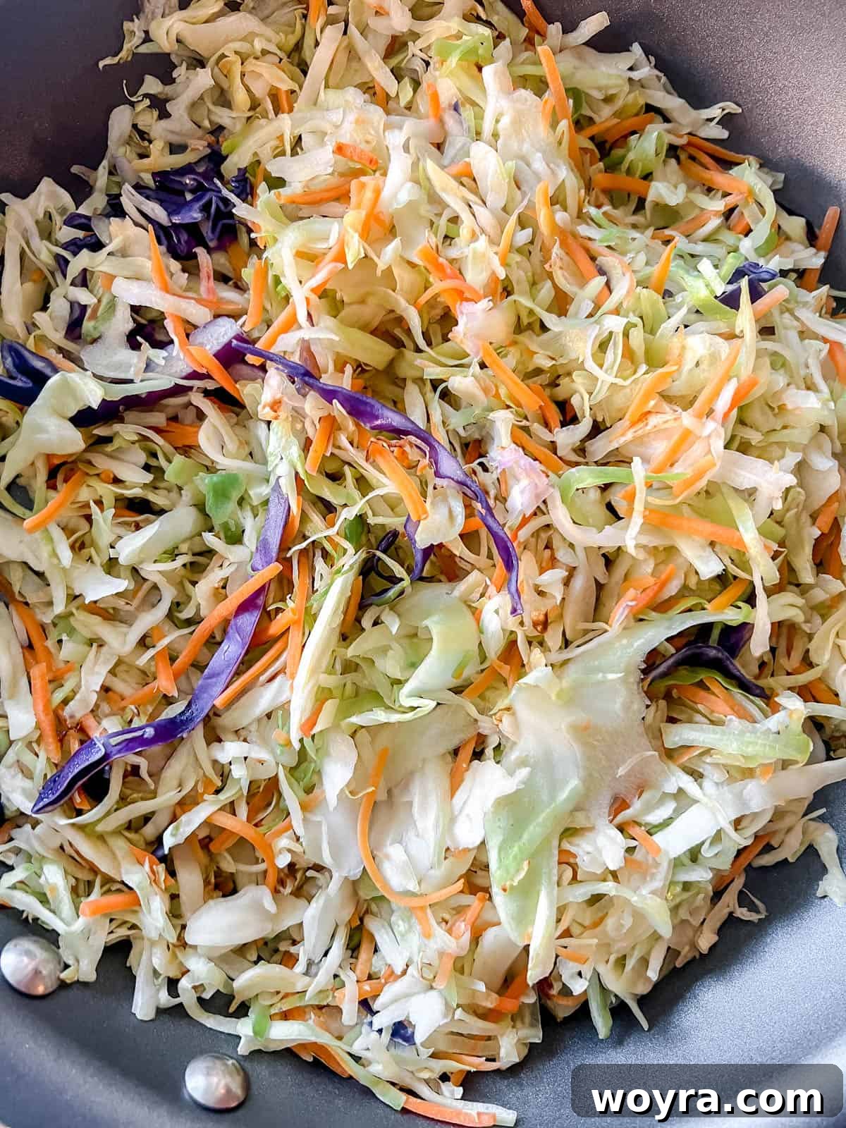 Vibrant Cabbage Slaw 8 Shredded cabbage and carrots gently sautéing in a pan with olive oil.