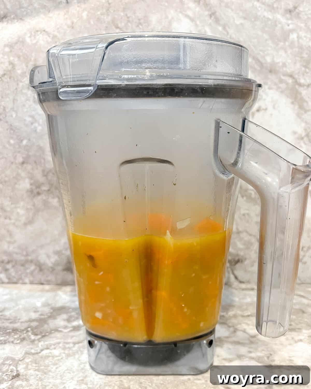 The cooked pumpkin and sweet potato soup mixture inside a blender, ready for blending into a smooth consistency.