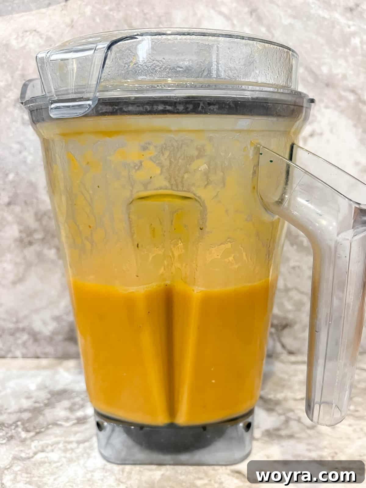 Creamy, smooth pumpkin and sweet potato soup filling a blender after being pureed to perfection.