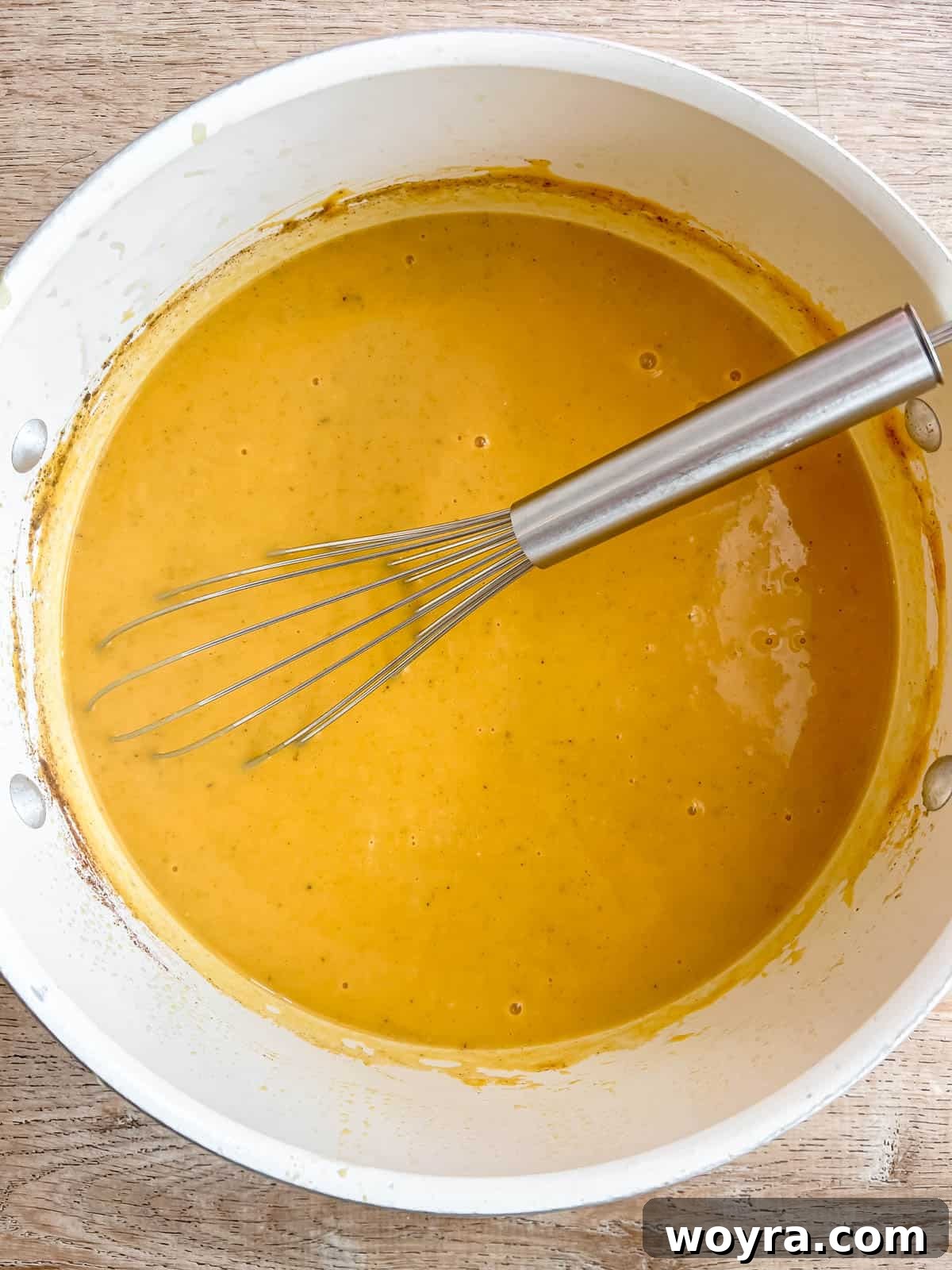 Sweet potato pumpkin soup being gently whisked in a large pot, ensuring all ingredients are well combined and smooth.