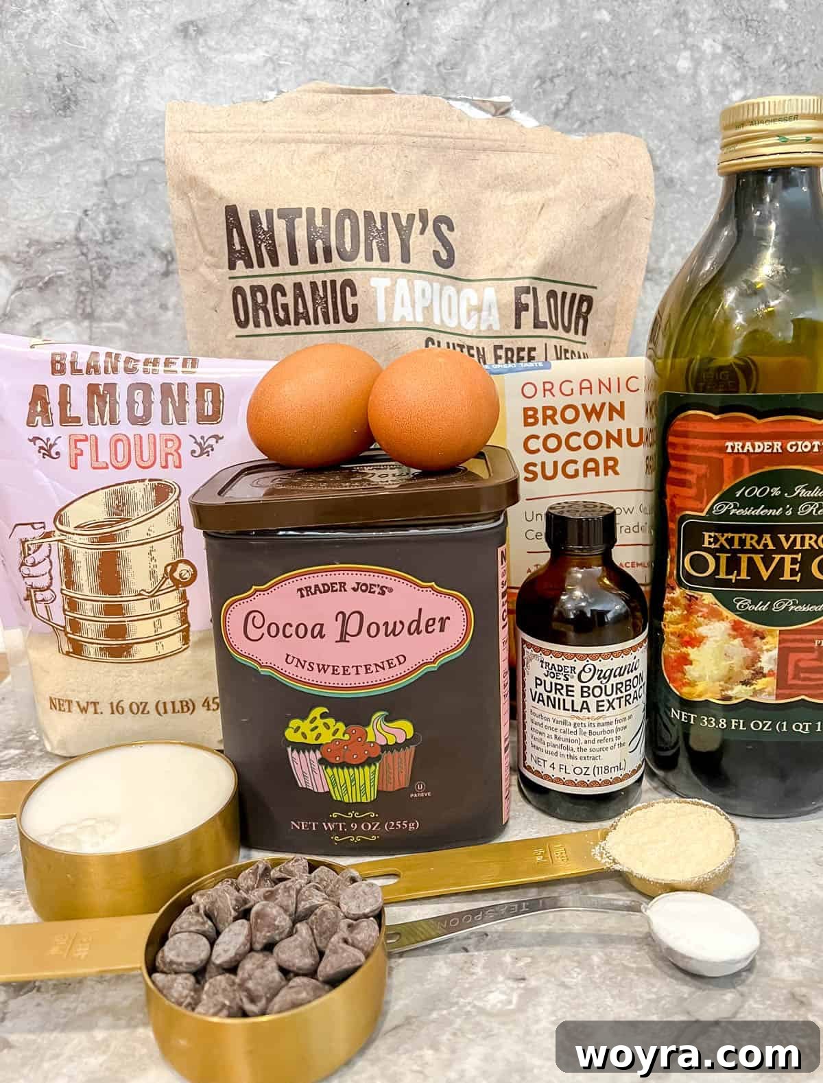Decadent Paleo Chocolate Muffins 4 Ingredients laid out for making gluten-free chocolate muffins, including flours, cocoa, and oils.