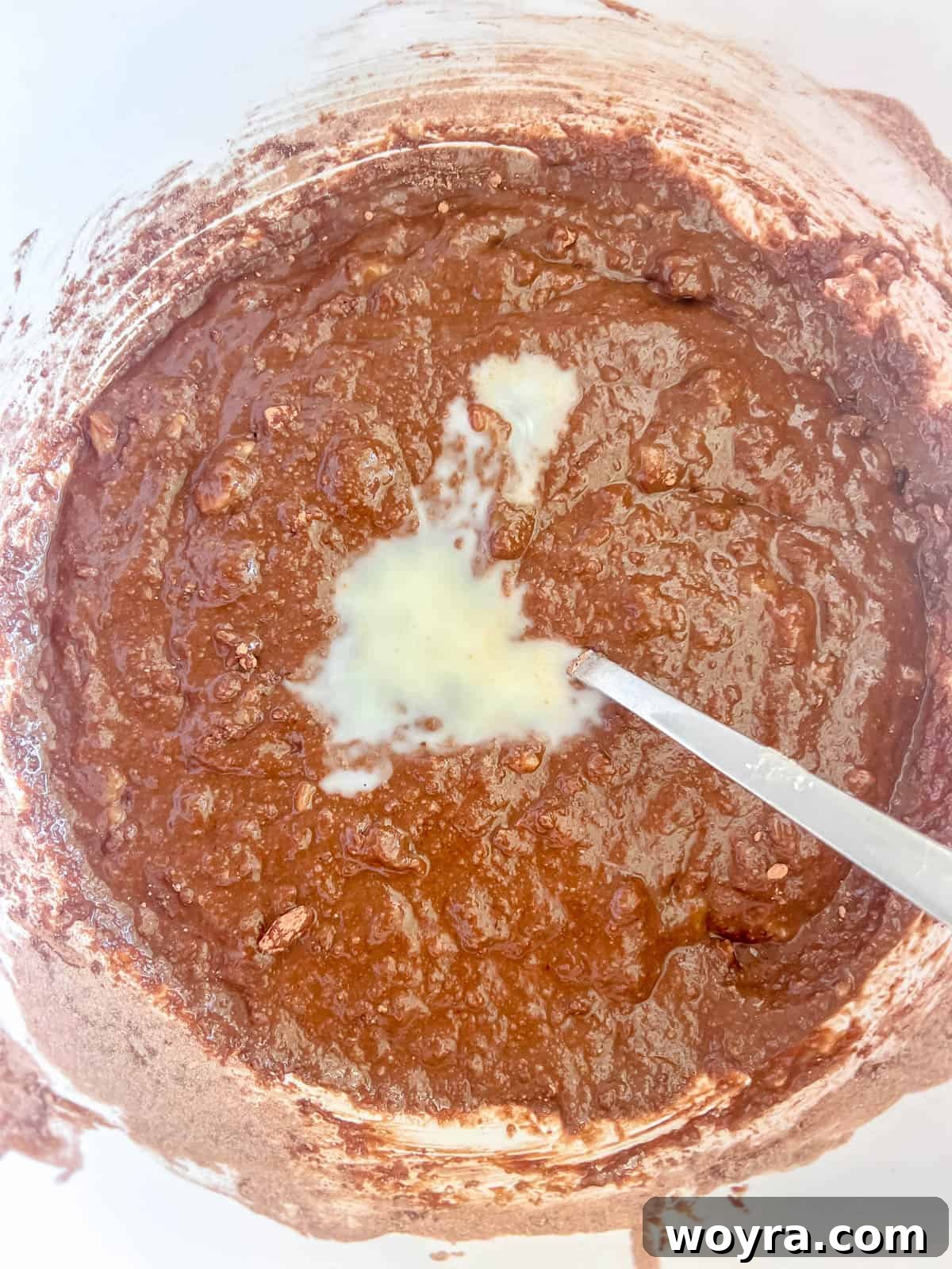 Decadent Paleo Chocolate Muffins 7 Wet and dry ingredients for chocolate muffins are mixed together in a bowl, forming a smooth batter.