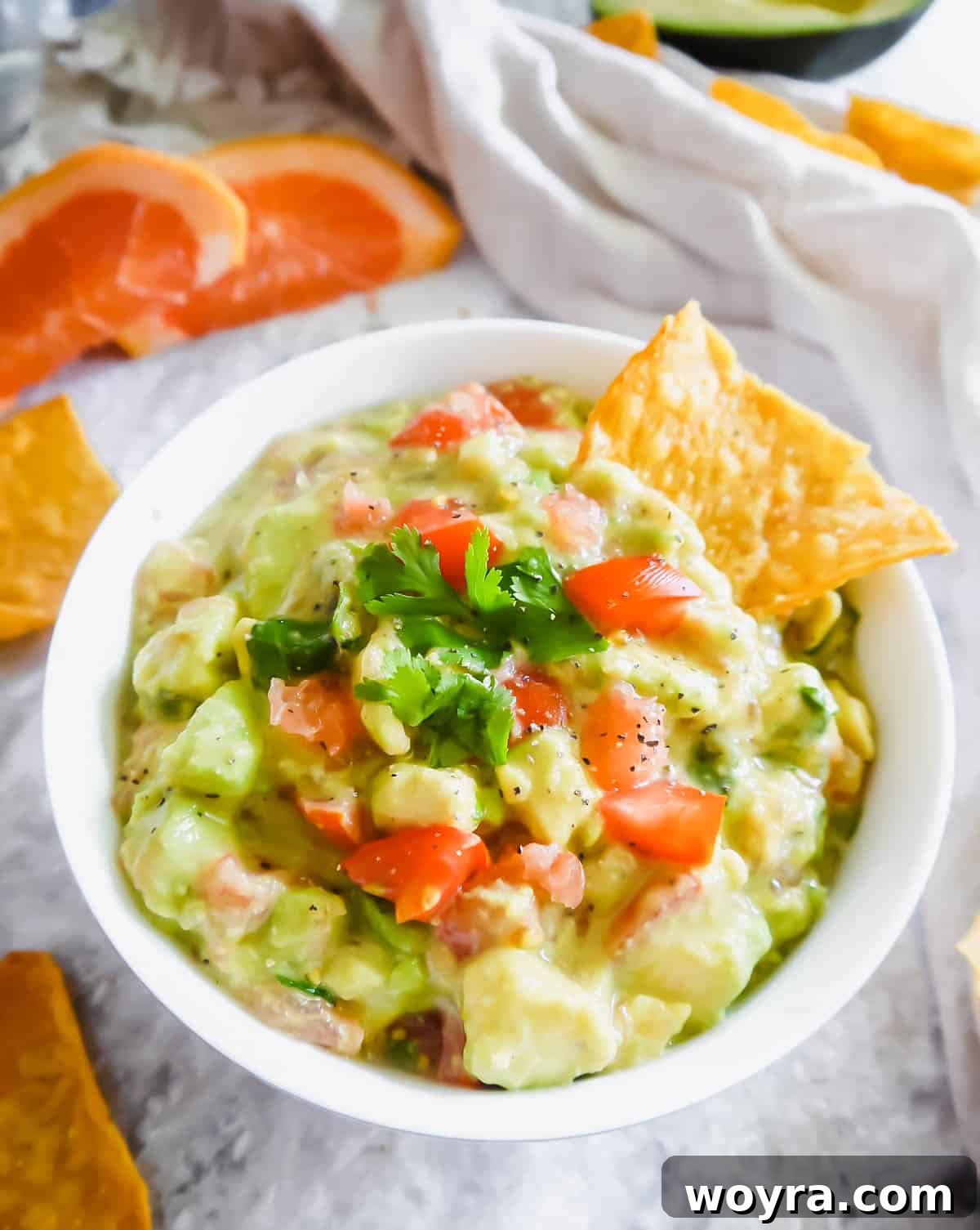 Citrus guacamole in a bowl with a chip inside, showcasing its vibrant color and inviting texture.