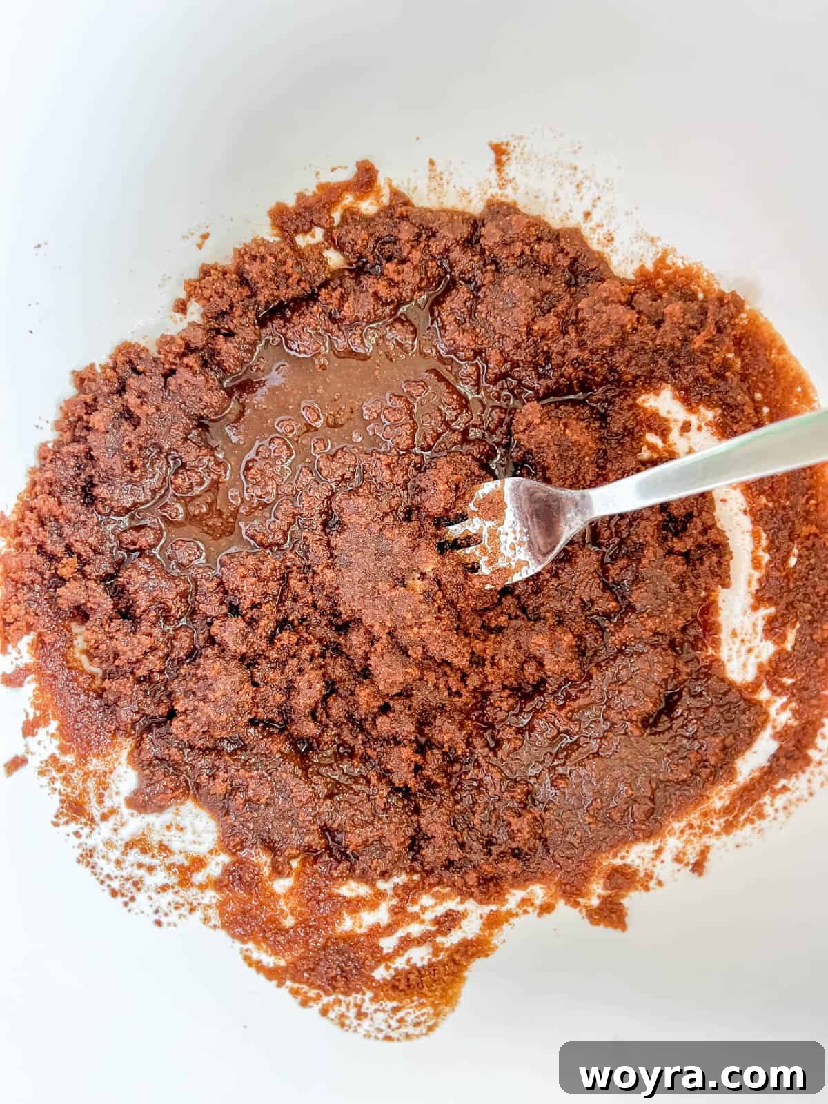 Coconut sugar being whisked into olive oil in a bowl.