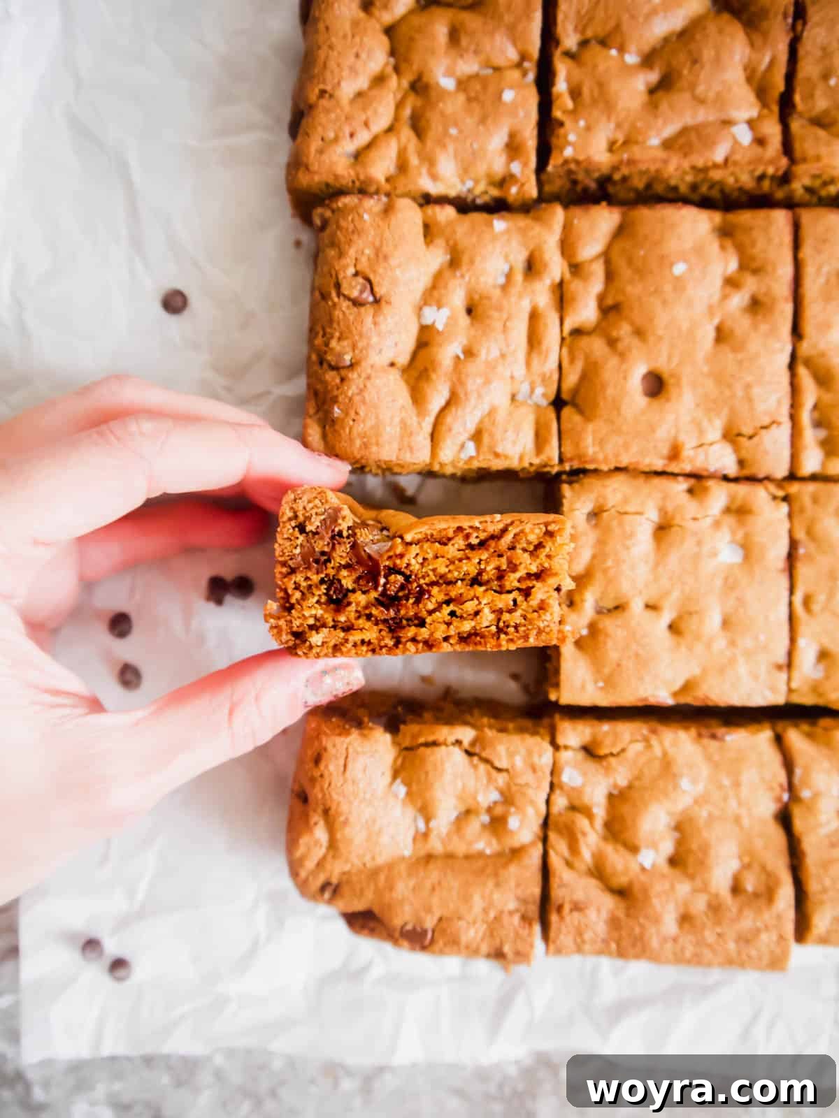 Primal Chocolate Chip Cookie Bars 10 A hand holding a single dairy-free chocolate chip cookie bar, showing its perfect texture and abundant chocolate chips.