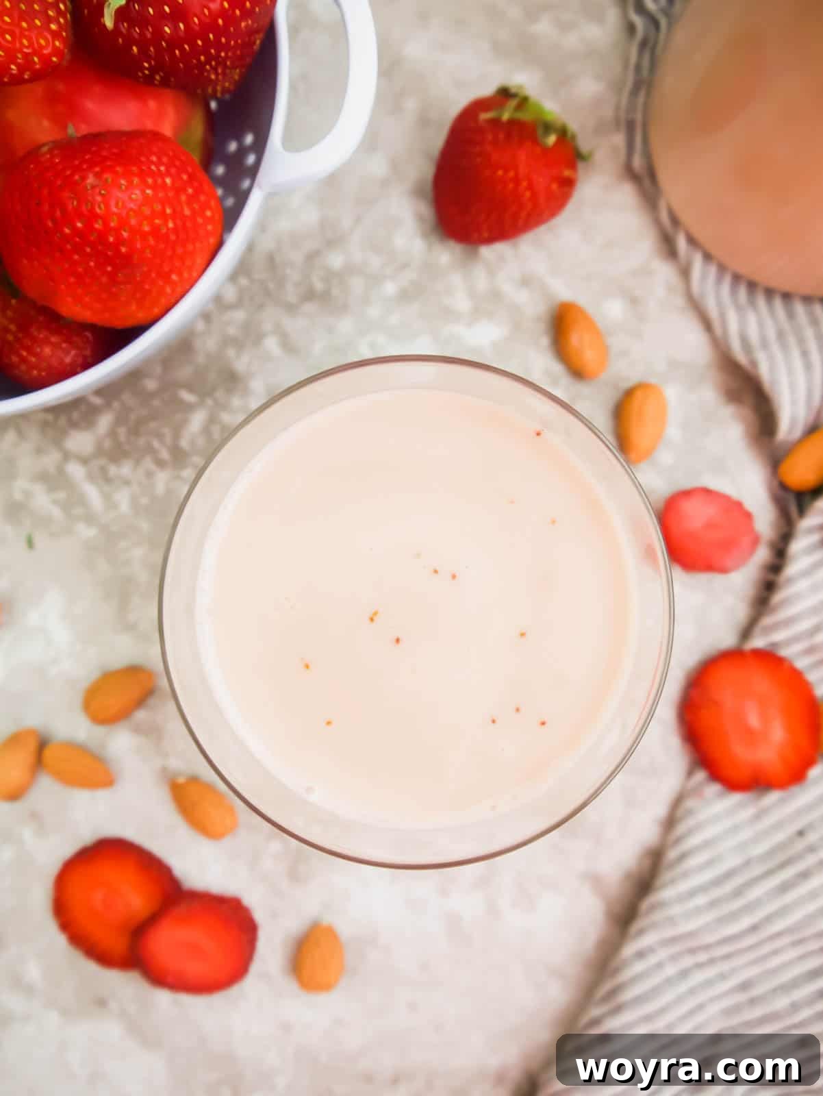 Homemade Strawberry Almond Milk: A Vegan Delight 15 A beautifully presented glass of homemade strawberry almond milk, garnished with fresh whole strawberries and mint leaves, on a light wooden background.
