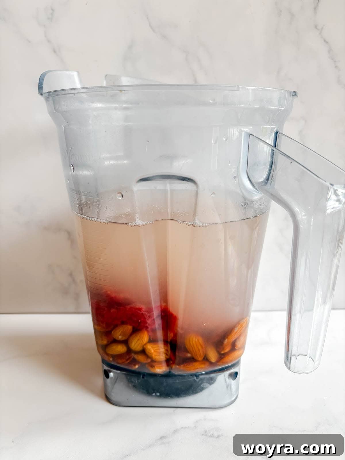 Homemade Strawberry Almond Milk: A Vegan Delight 8 Soaked almonds, filtered water, and the leftover strawberry pulp combined in a blender, ready to be processed into milk.