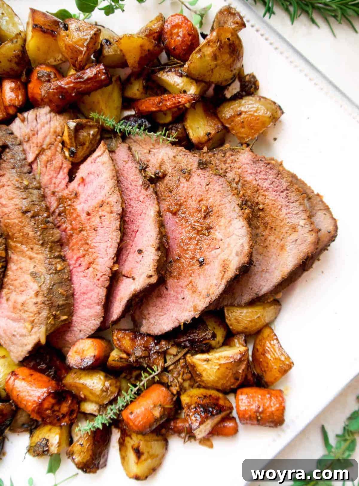 Garlic Herb Beef Heart of Shoulder Roast 2 Slices of perfectly cooked Garlic and Fresh Herb Beef Clod Heart of Shoulder Roast on a plate, accompanied by roasted carrots and potatoes, ready to be served.