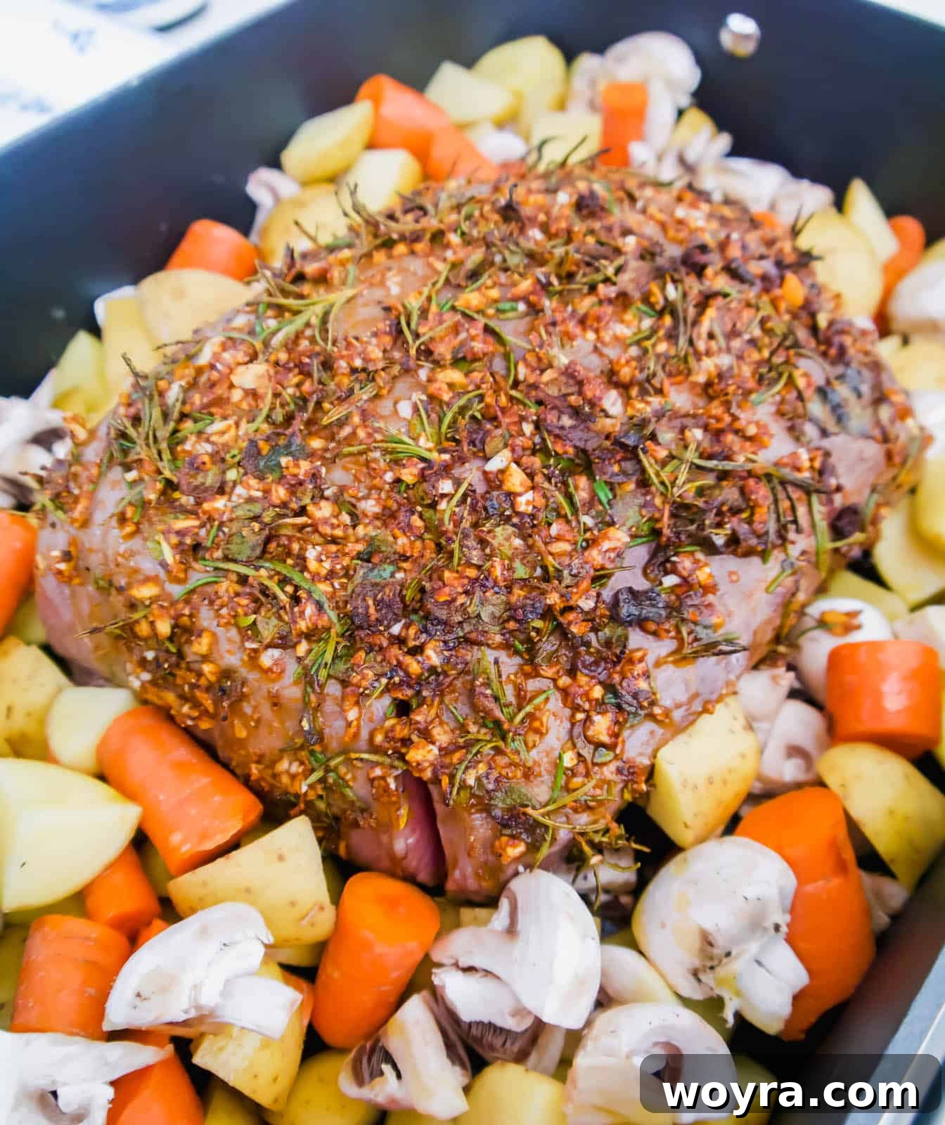 Garlic Herb Beef Heart of Shoulder Roast 6 Quartered potatoes, sliced carrots, and mushrooms arranged around the beef clod roast in the roasting pan.