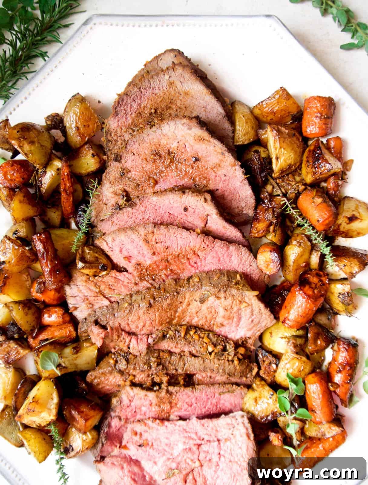 Garlic Herb Beef Heart of Shoulder Roast 9 Generous slices of succulent shoulder clod roast presented on a plate, surrounded by perfectly roasted potatoes and carrots, ready for a family dinner.