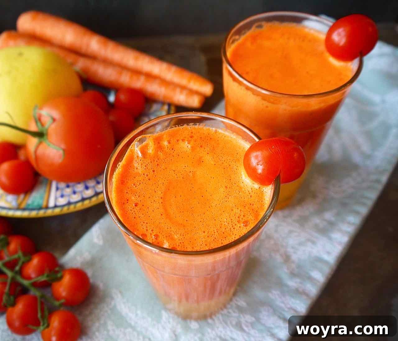 Rejuvenating Tomato Carrot Fusion 4 Two glasses of freshly prepared orange carrot tomato juice, with a vibrant, layered look, served on a light wooden tray.