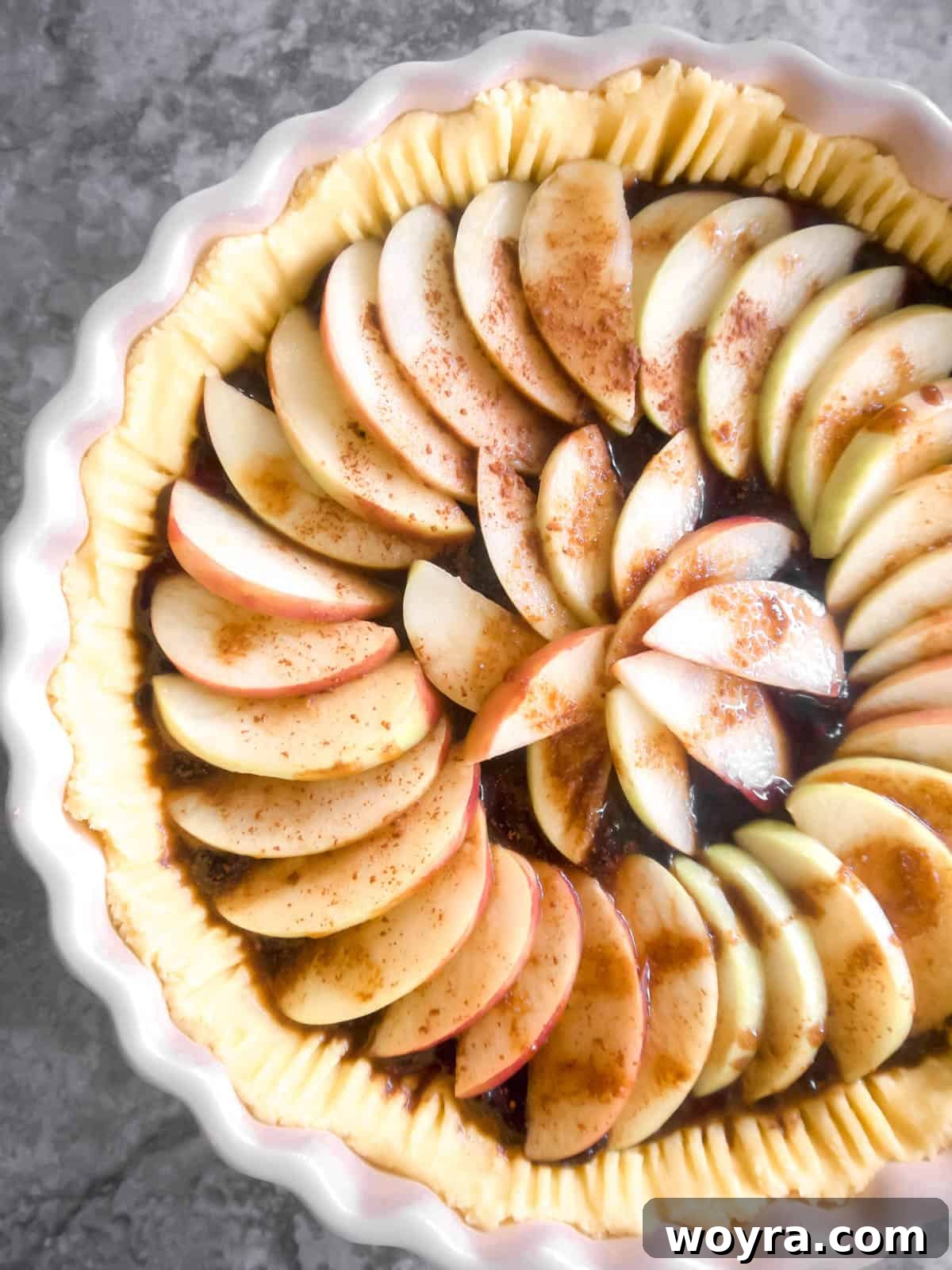Ancestral Apple Indulgence 8 Thinly sliced apples arranged in a circular pattern on top of the jam, before baking.