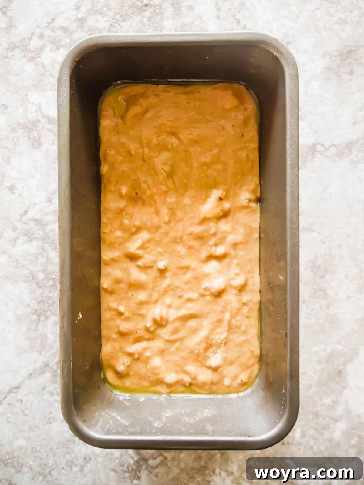 Banana bread coffee cake batter being poured into a loaf tin.