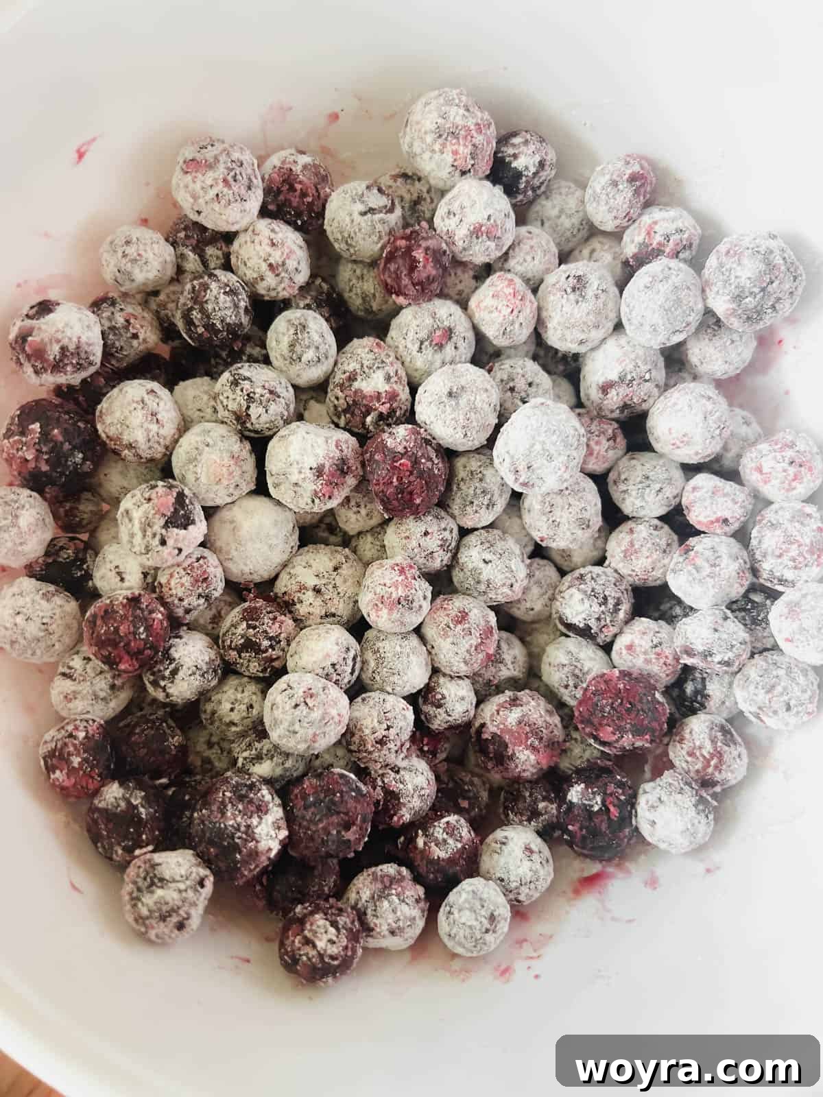 Grain-Free Blueberry Bliss Muffins 9 Frozen blueberries coated with flour in a bowl.