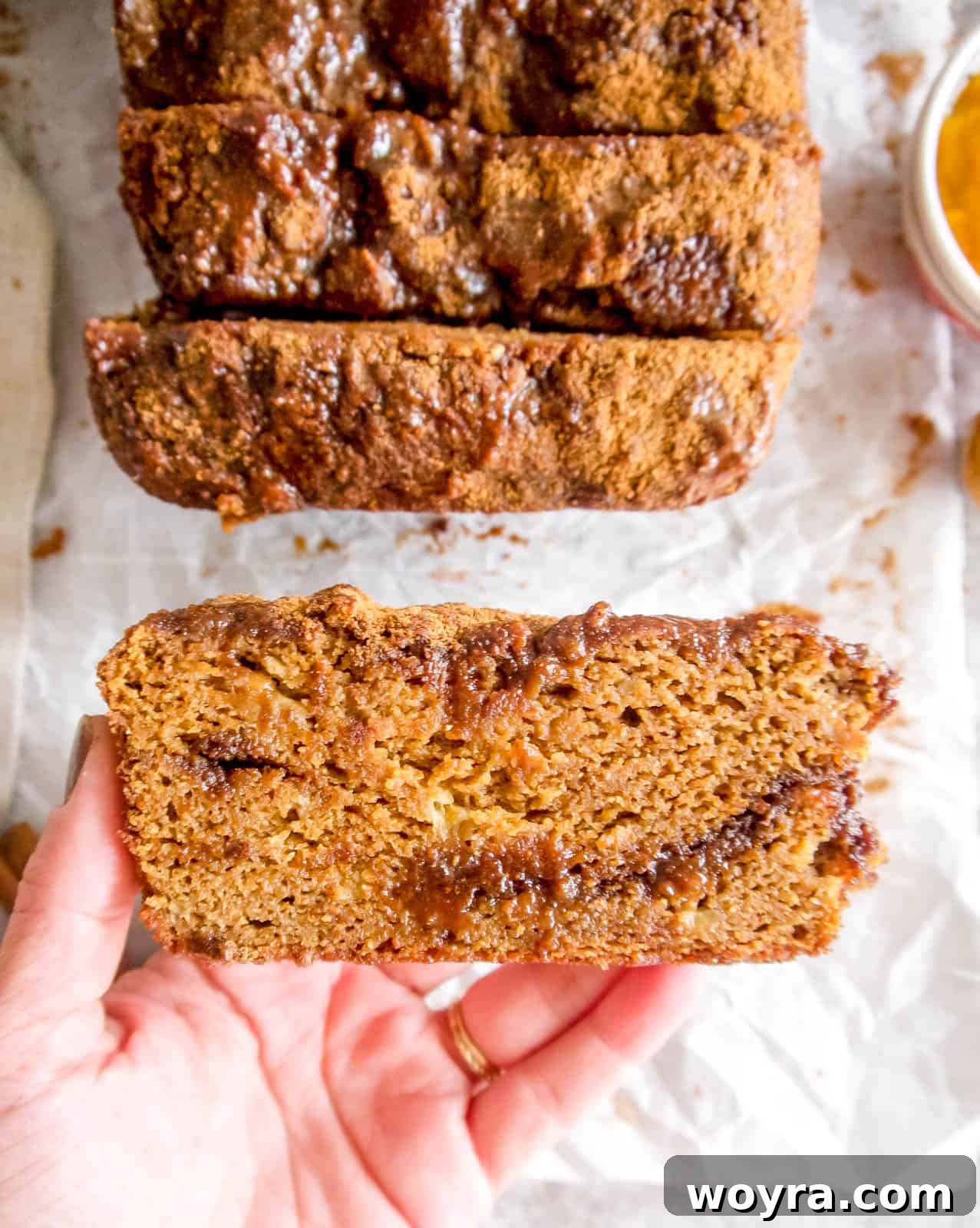 Wholesome Paleo Cinnamon Swirl Pumpkin Banana Bread 7 Hands holding a slice of Cinnamon Swirl Paleo Pumpkin Banana Bread, showcasing its delicious texture and maple glaze.