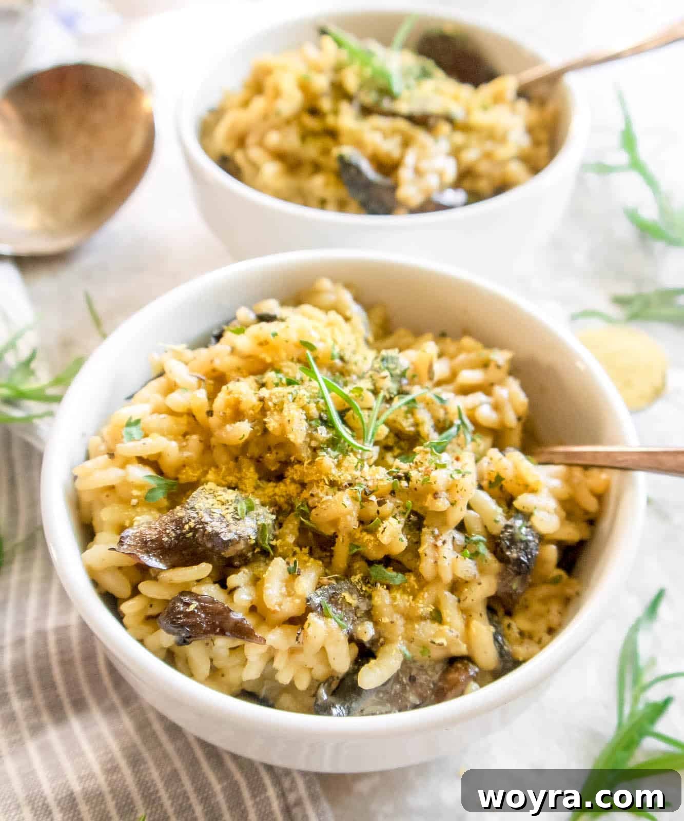 Two bowls of Dairy-Free Mushroom Risotto with spoons ready to be enjoyed.