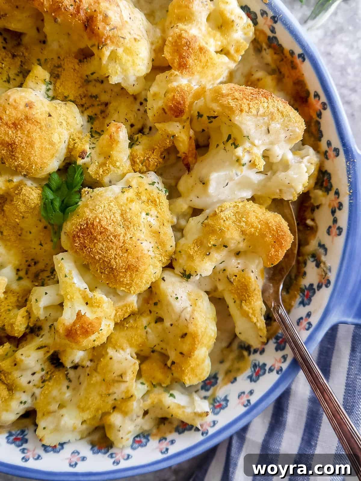 Freshly baked Vegan cauliflower gratin, bubbling and golden brown, with a spoon ready to scoop a portion.