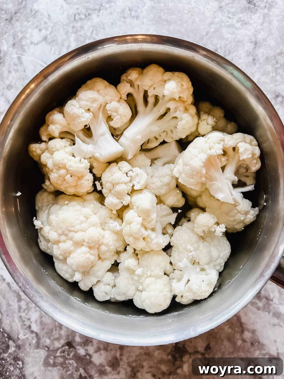 Cauliflower florets in a pot of boiling water, preparing for blanching.