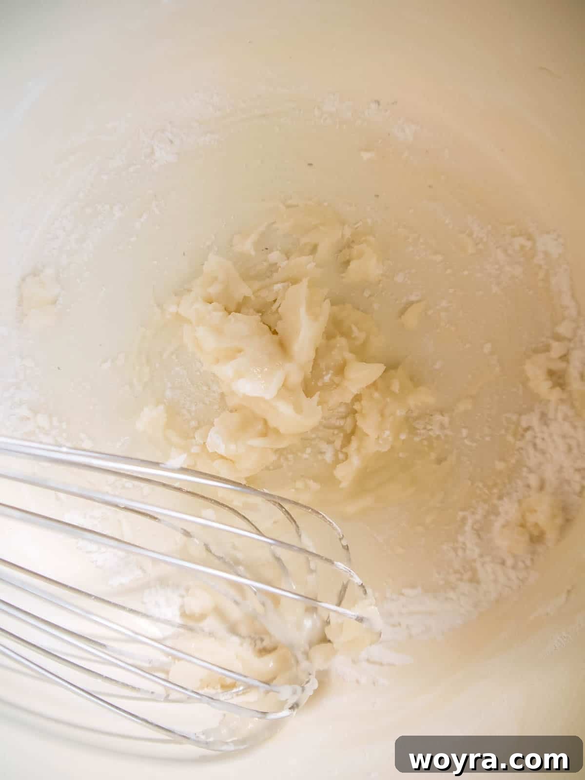A pan on the stove, showing olive oil, tapioca flour, and coconut flour being whisked together to form a roux.