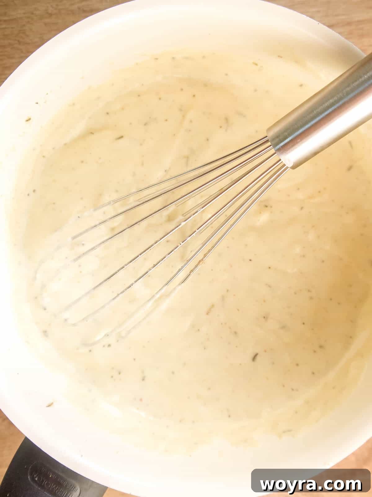 The pan from Step 2, now with coconut cream and almond milk added to the flour mixture, being whisked vigorously.