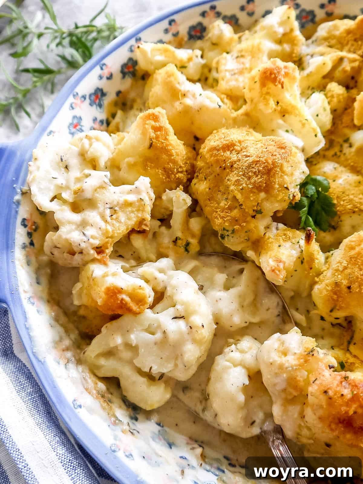 A close-up of a dairy-free cauliflower bake with a serving spoon, showing the creamy interior and golden topping.