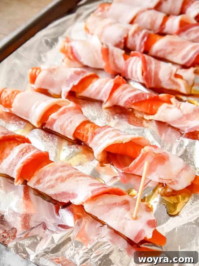 Paleo Gluten Free Maple Bacon Roasted Carrots 7 Visual guide: Carrots fully wrapped in bacon and lined up on a baking sheet, ready for seasoning.