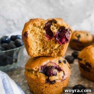 Dairy-free Blueberry Muffins stacked on top of each other. There is a bite taken out of the top muffin.