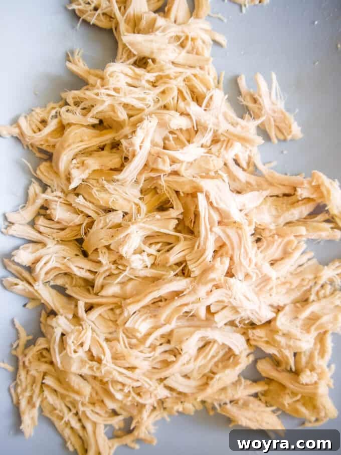 Cooked chicken breasts removed from the slow cooker, ready for shredding.