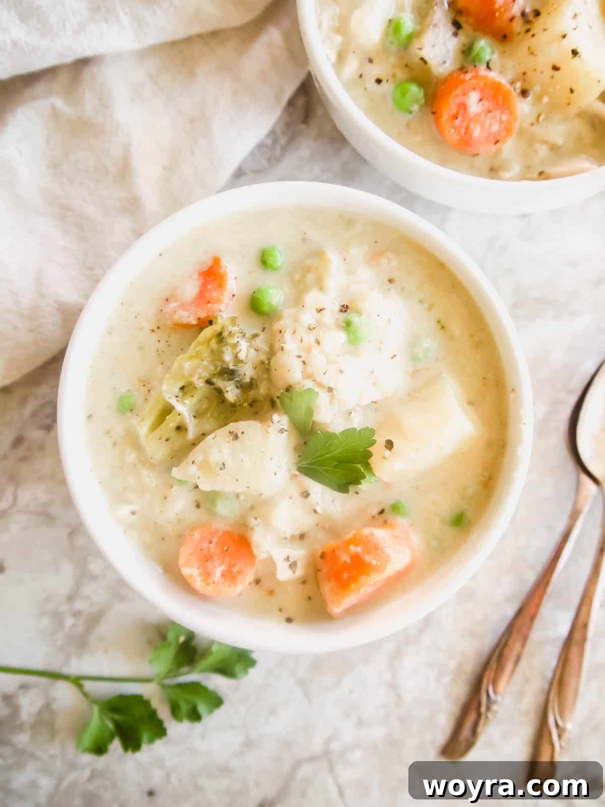 A close-up shot of the creamy chicken pot pie soup in a rustic bowl, with a spoon dipping in.