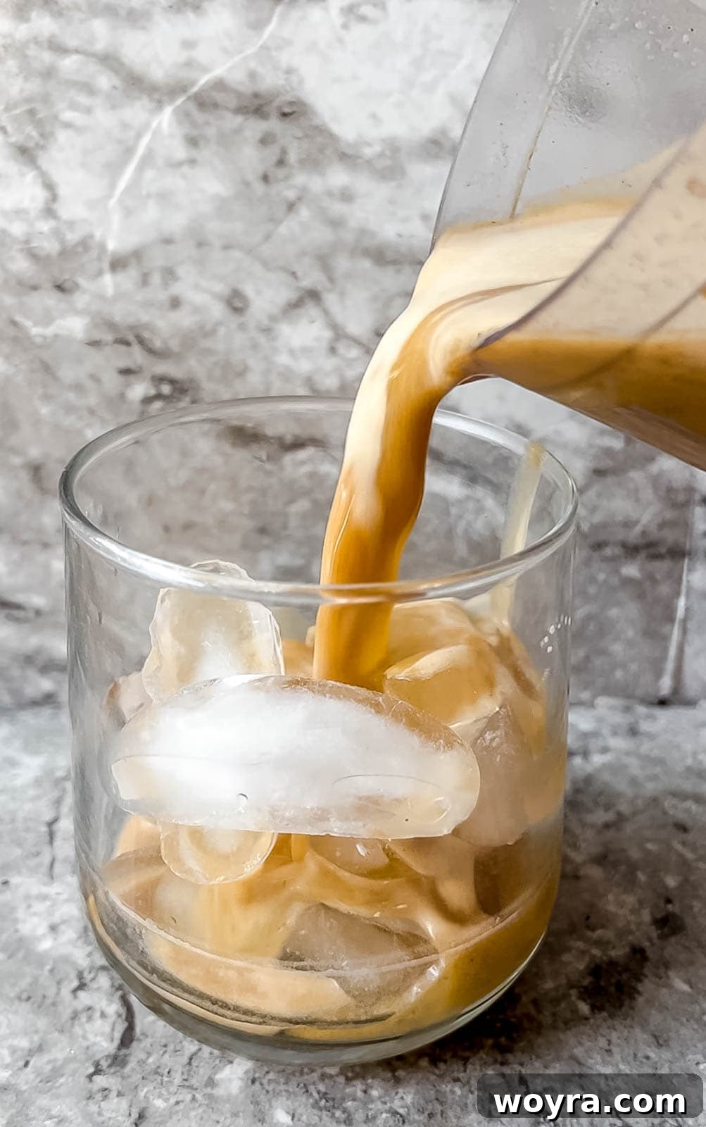 Pouring a pumpkin spice white Russian into a cup over ice.